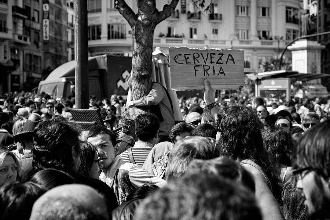 A crowd beneath a sign advertising cold beer.